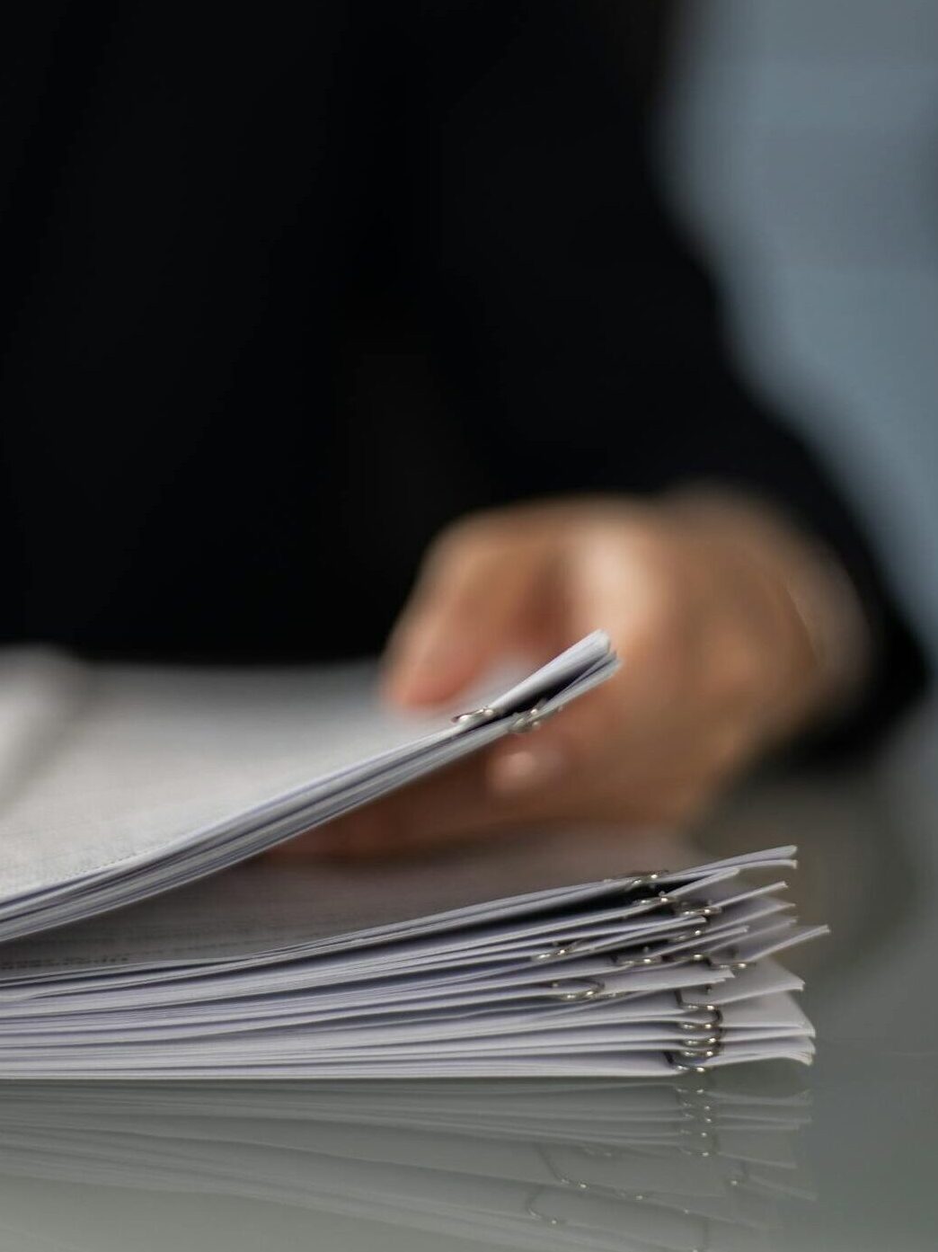 Professional hand holding multiple stacks of business documents, symbolizing thorough debt recovery analysis and understanding